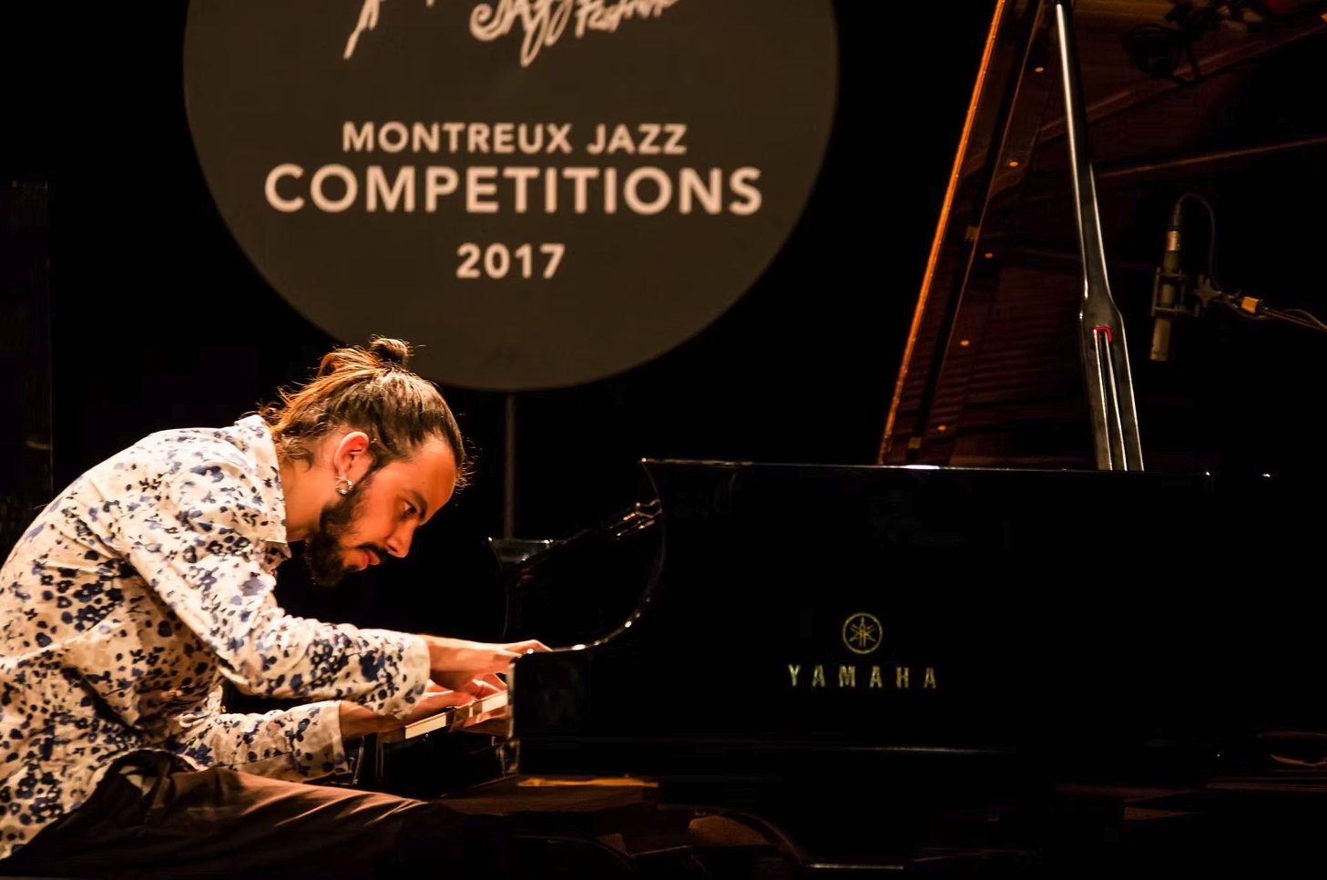 Salomão ao piano visto de costas, com a plateia à frente, no Montreux Jazz Competitions