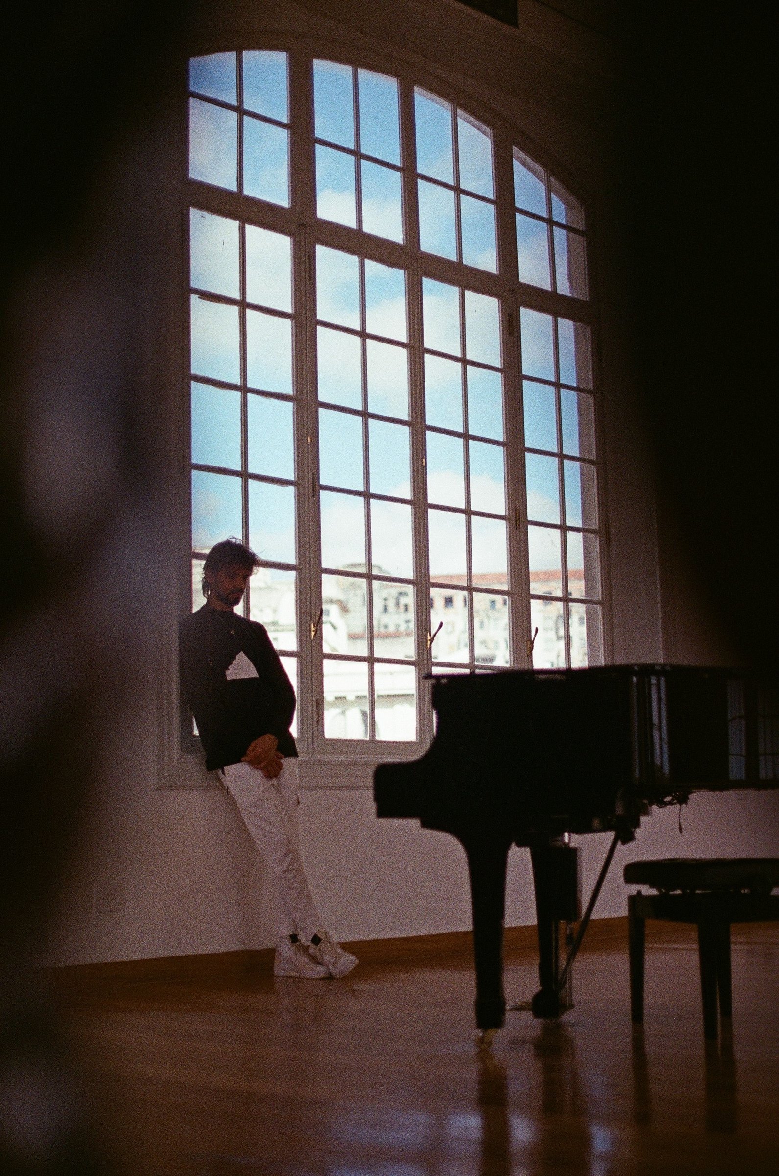 Salomão Soares ao lado do piano, contraluz de janela