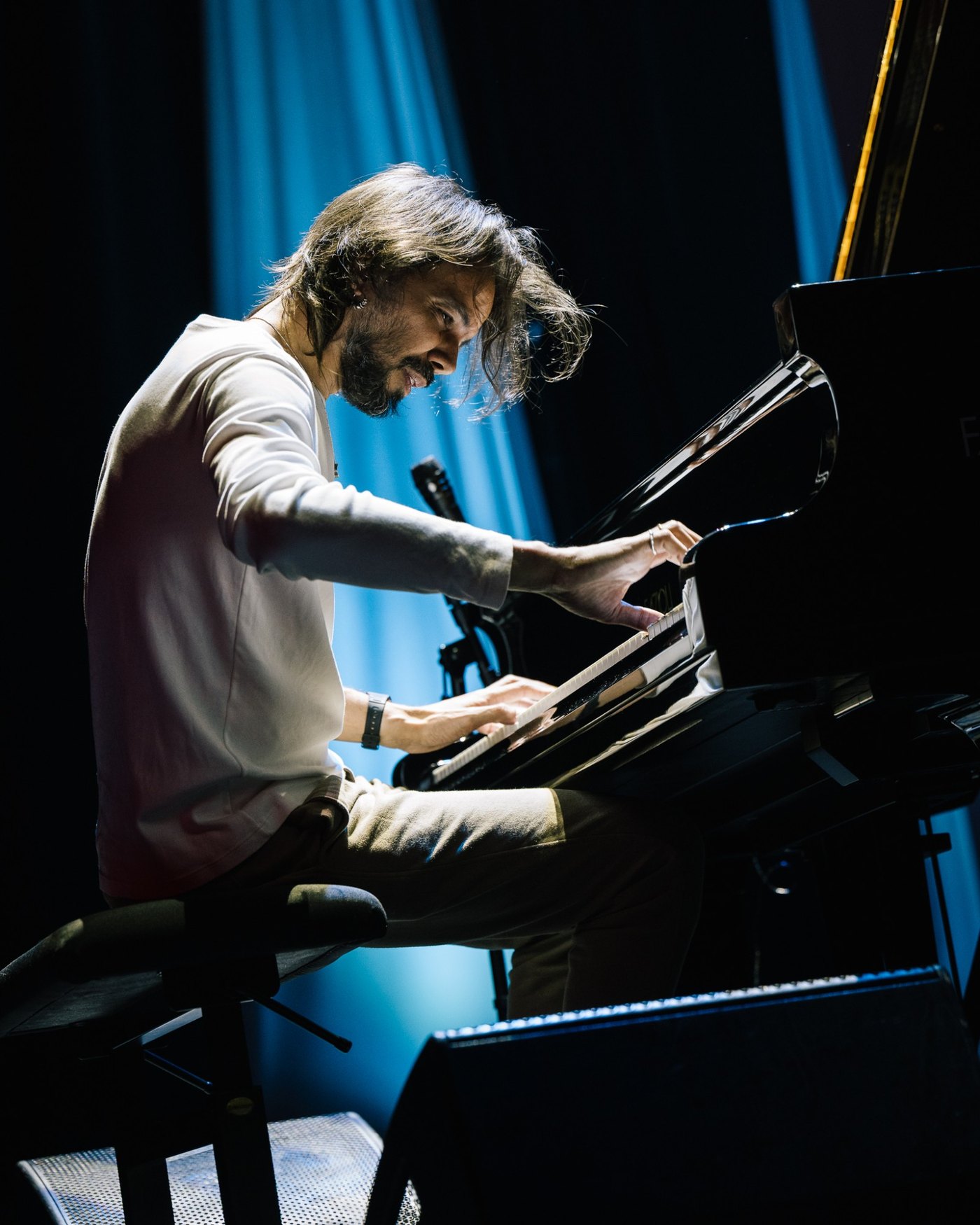 Salomão Soares at the grand piano at the Cape Town International Jazz Festival, leaning over the keyboard, under blue stage light